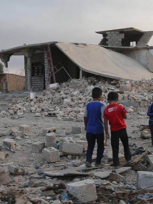 Die Kinder im Alter von ca. sechs Jahren spielen vor einem völlig zerstören Gebäude. 