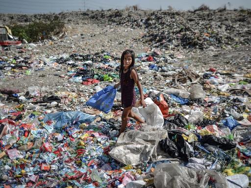 Ein Mädchen läuft mit einer Plastiktüte in der Hand über eine Müllhalde auf den Philippinen