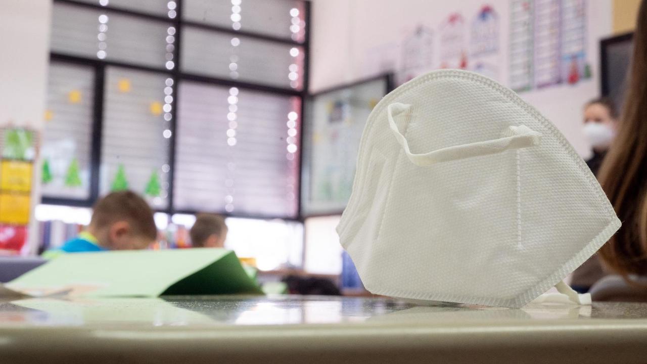 Eine FFP2-Maske liegt in einer ersten Klasse an einer Grundschule auf einem Tisch.