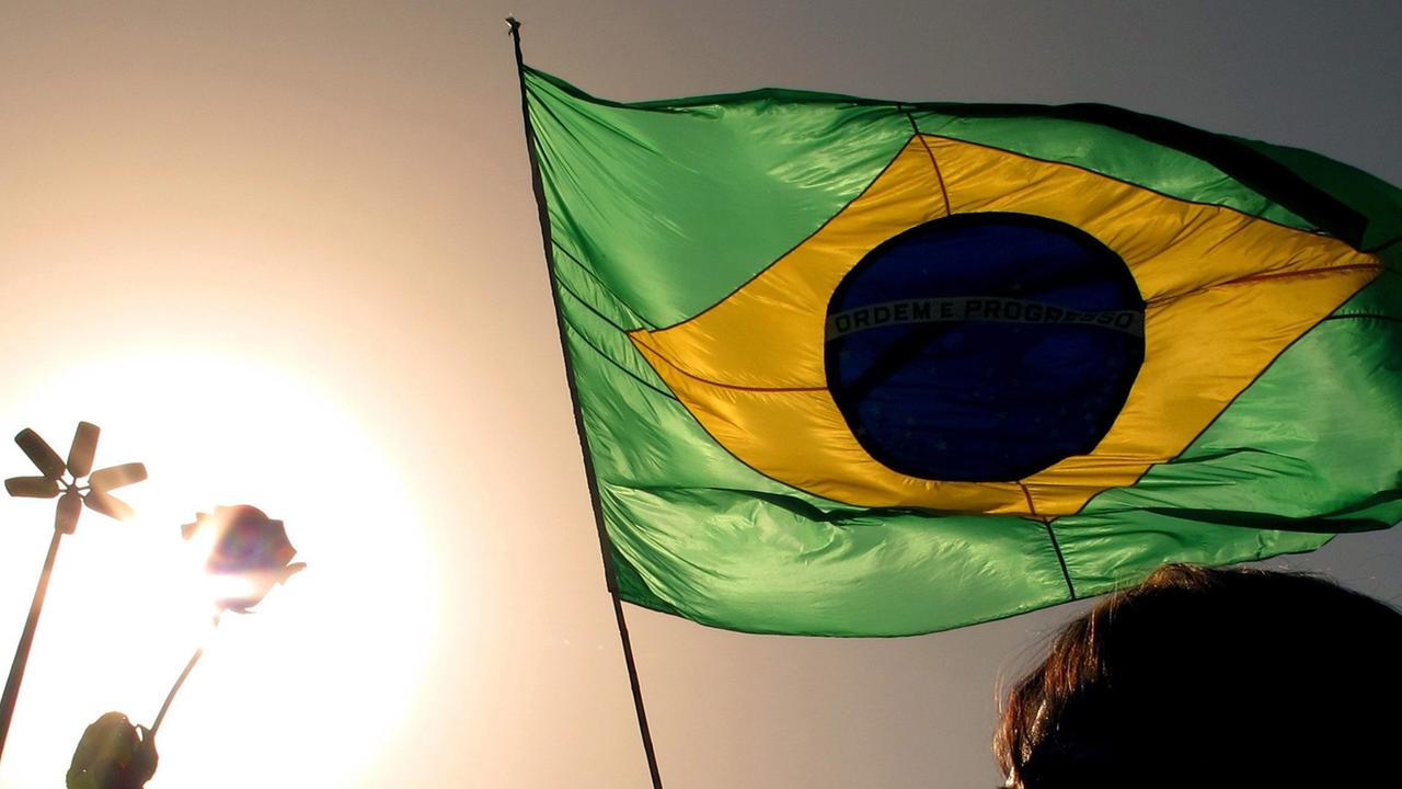 Im Sonnenuntergang hält ein Mann die Flagge von Brasilien. Im Sonnenuntergang hält ein Mann die Flagge von Brasilien.