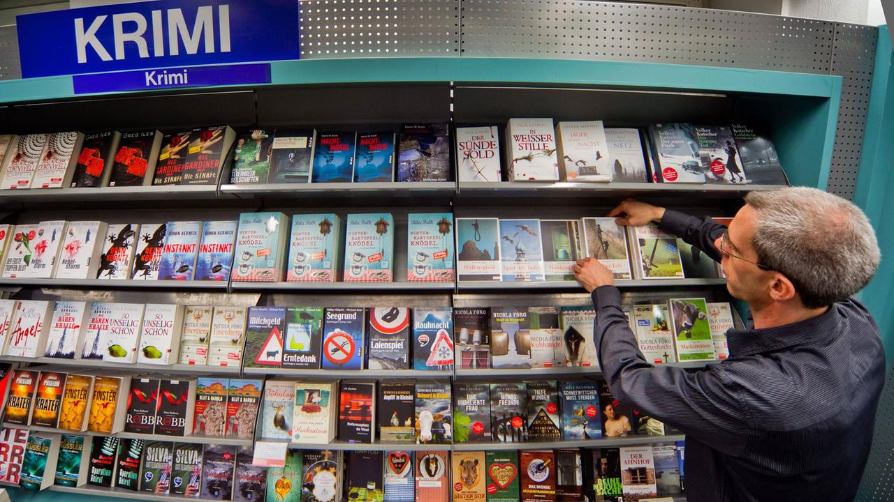 Ein Mitarbeiter vor dem Regal mit Regionalkrimis in der Buchhandlung Hugendubel in München