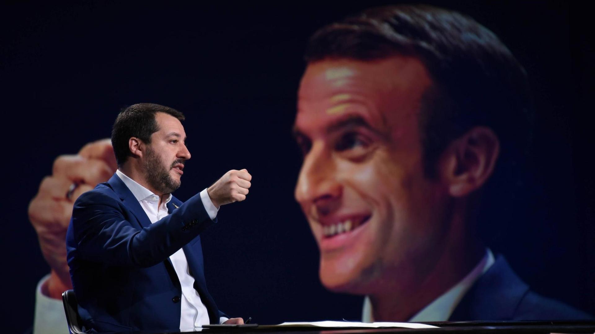 Matteo Salvini spricht in einer italienischen TV-Show. Hinter ihm eine große Einblendung Emmanuel Macrons Matteo Salvini spricht in einer italienischen TV-Show. Hinter ihm eine große Einblendung Emmanuel Macrons