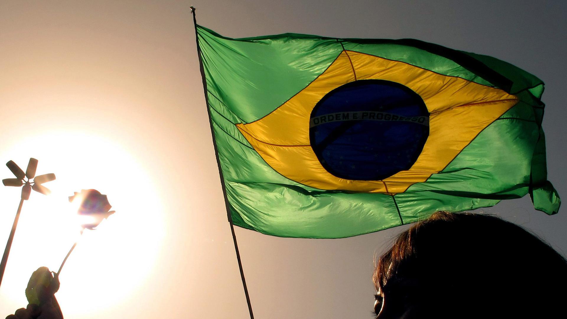 Im Sonnenuntergang hält ein Mann die Flagge von Brasilien. Im Sonnenuntergang hält ein Mann die Flagge von Brasilien.