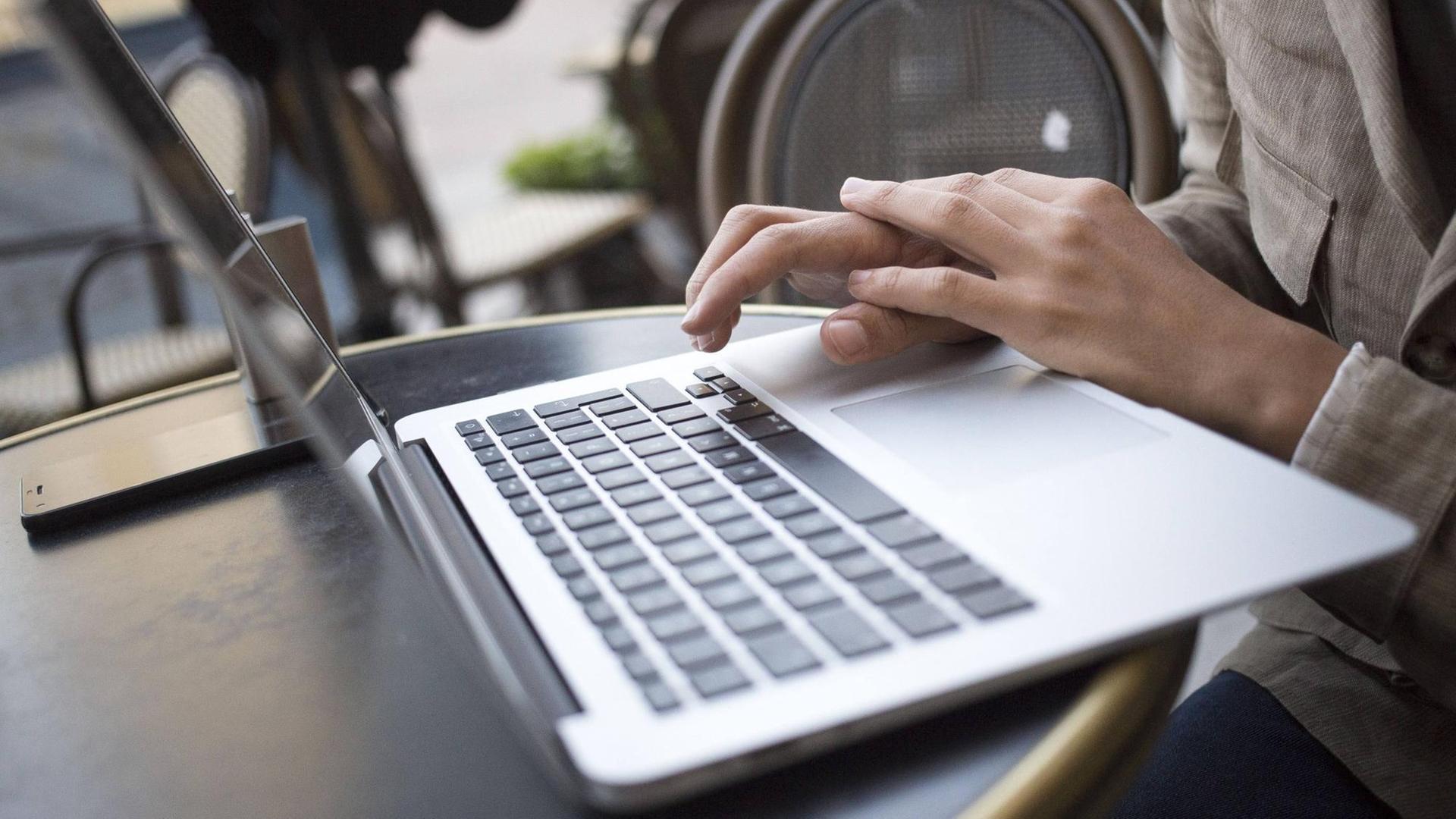 Ein Mann sitzt an einem Laptop und tippt auf der Tastatur Ein Mann sitzt an einem Laptop und tippt auf der Tastatur