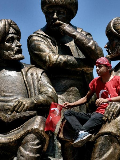 Ein junger Mann sitzt auf einer Statue für Sultan Mehmed II im Sarachane-Park von Istanbul während einer Demonstration für den türkischen Präsidenten Erdogan am 19.7.2016.