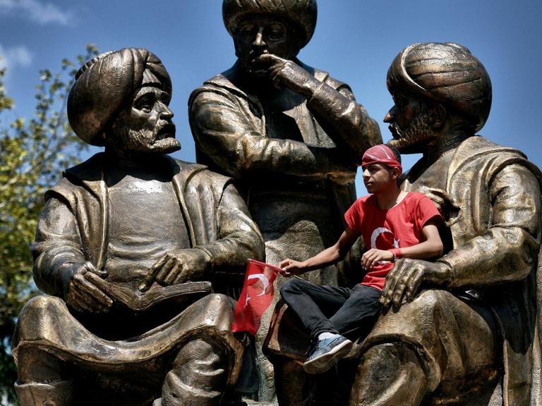 Ein junger Mann sitzt auf einer Statue für Sultan Mehmed II im Sarachane-Park von Istanbul während einer Demonstration für den türkischen Präsidenten Erdogan am 19.7.2016.