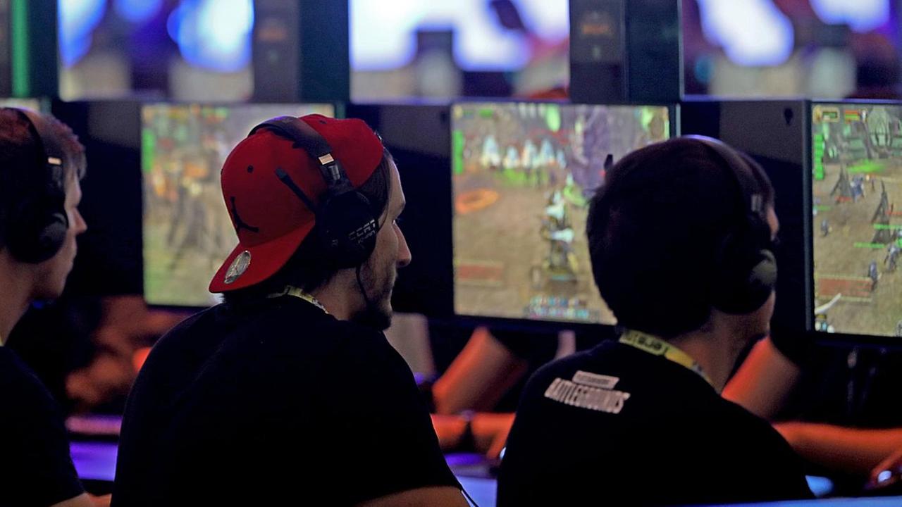 Besucher der Gamescom spielen vor Monitoren. Besucher der Gamescom spielen vor Monitoren.