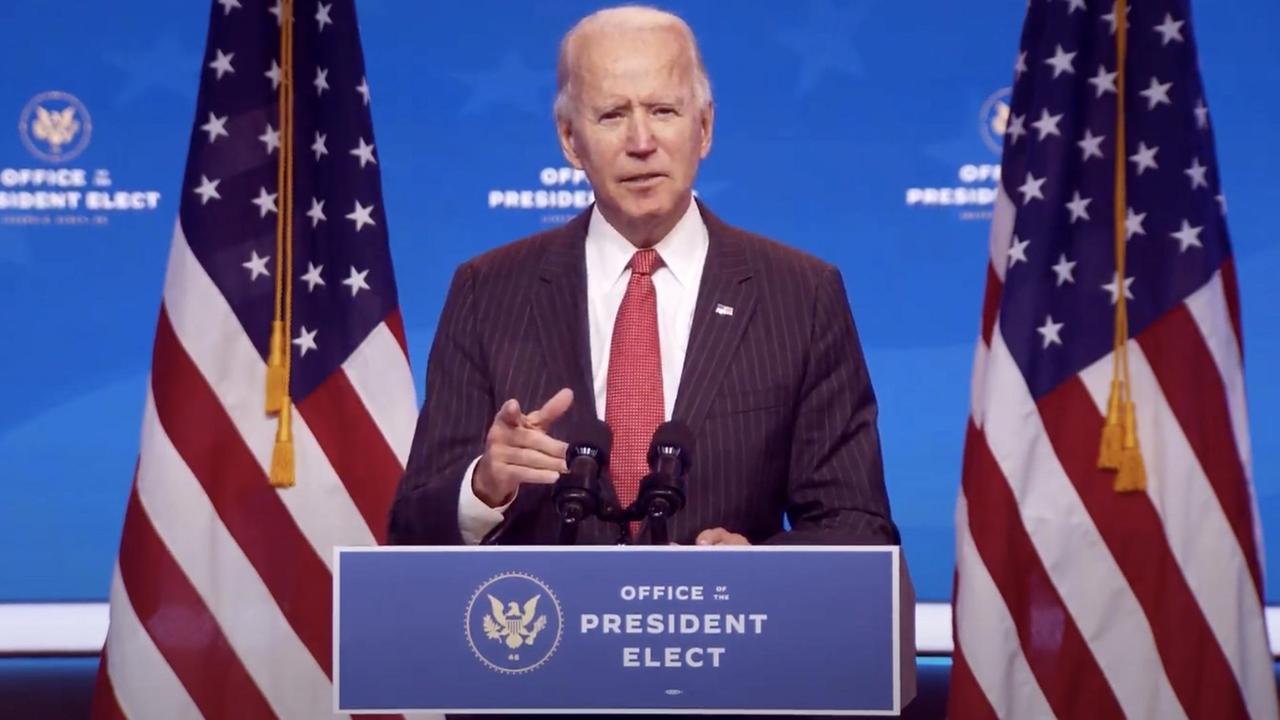 Joe Biden hält eine Rede, neben ihm stehen US-Flaggen