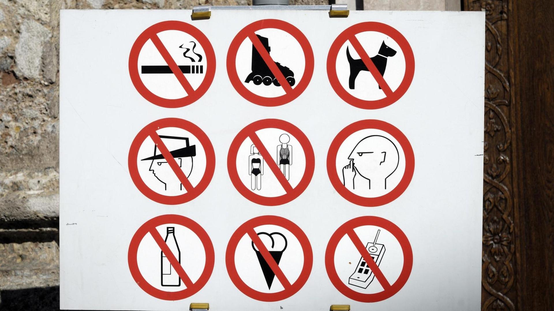 Das Verbotsschild vor dem Dom zu St. Jakob in Innsbruckverbietet: Rauchen, Inlineskaten, Hunde, Hüte, Badekleidung, Flaschen, Eis und Handys. Außerdem wird dazu aufgefordert, ruhig zu sein.