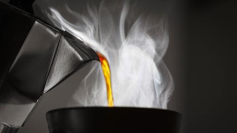 Kaffee wird im Gegenlicht in eine Tasse eingeschenkt.
