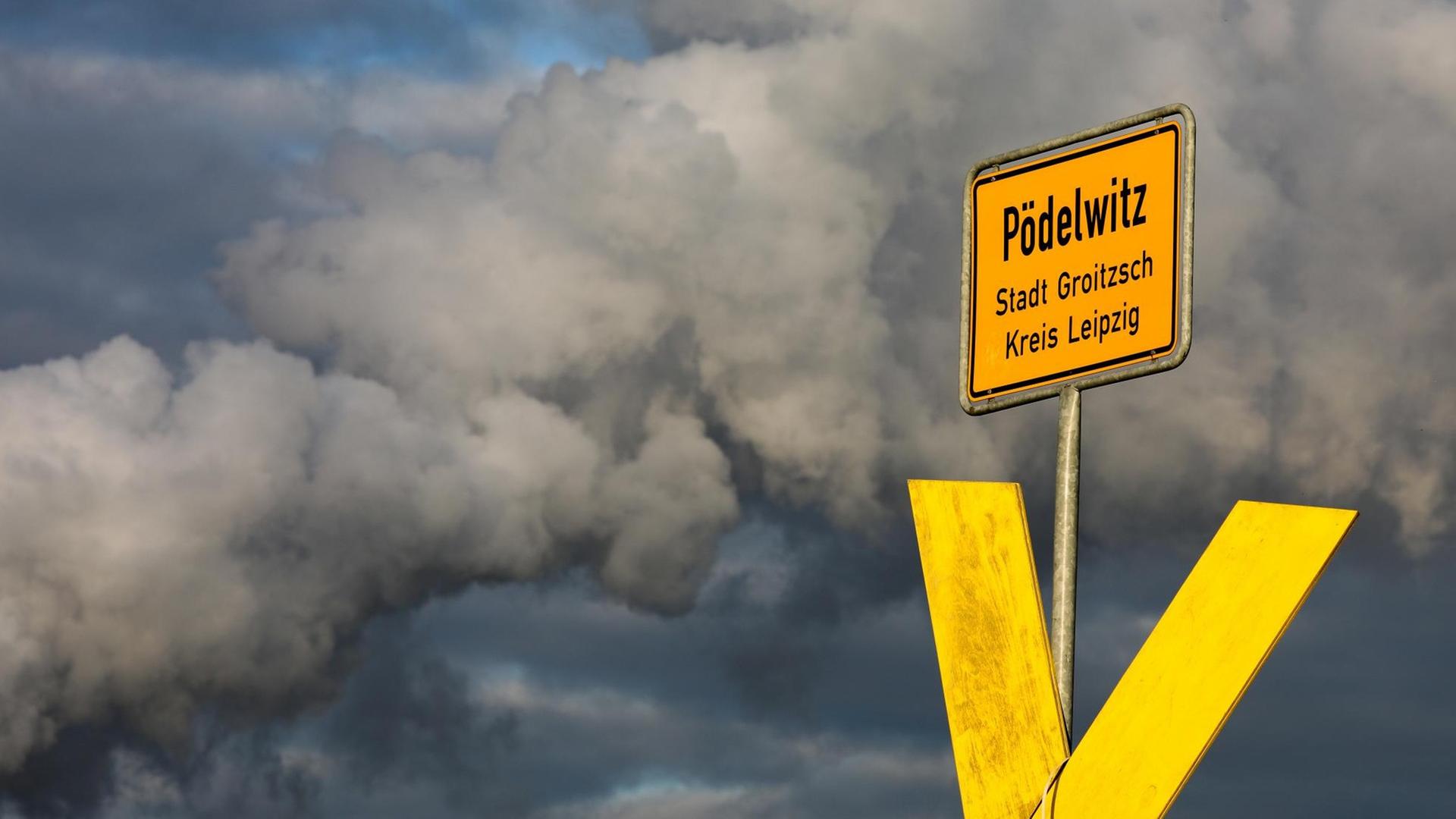 Ein gelbes X steht am Ortsschild von Pödelwitz, dahinter steigt der Dampf aus den Kühltürmen des Kraftwerks Lippendorf auf.