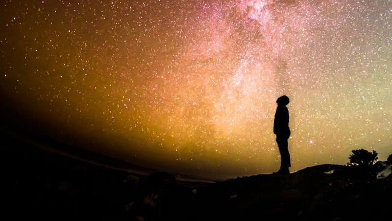 Silhouette eines Menschen, der ins farbenprächtige All blickt. Silhouette eines Menschen, der ins farbenprächtige All blickt.