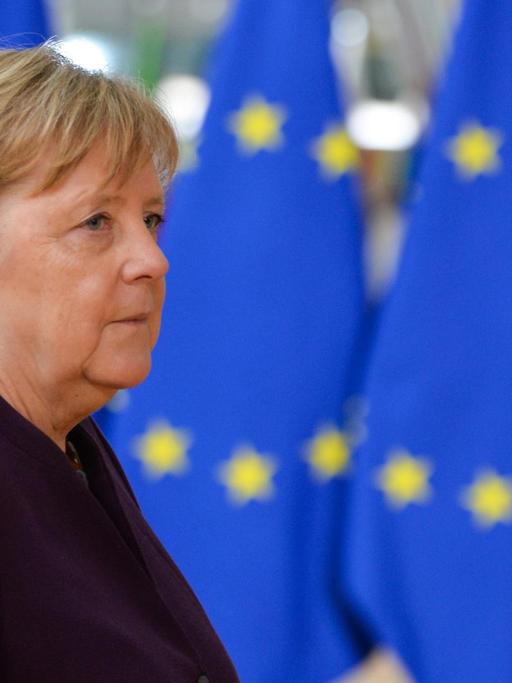 Bundeskanzlerin Merkel steht vor mehreren EU-Flaggen.