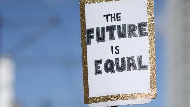 Das Foto zeigt eine Menge von Demonstrantinnen und ein Plakat mit der Aufschrift "Plakat The Future Is Equal" auf dem Internationalen Frauentag unter dem Motto Feiern Streiken Weiterkaempfen am 8. Maerz in Berlin. Das Foto zeigt eine Menge von Demonstrantinnen und ein Plakat mit der Aufschrift "Plakat The Future Is Equal" auf dem Internationalen Frauentag unter dem Motto Feiern Streiken Weiterkaempfen am 8. Maerz in Berlin.