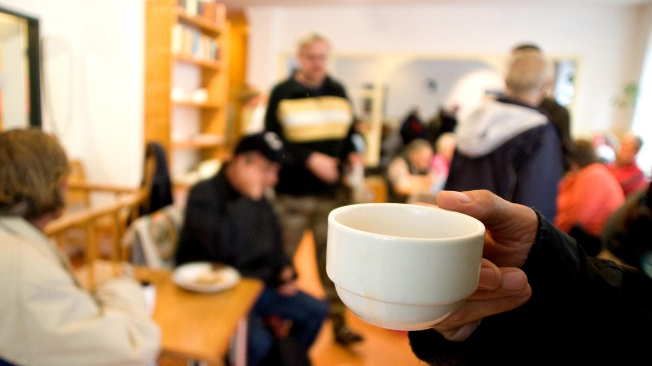 Bedürftige Menschen in der Wohnungslosen-Tagesstätte "Warmer Otto" der Berliner Stadtmission, im Vordergrund ist eine Tasse zu sehen. Bedürftige Menschen in der Wohnungslosen-Tagesstätte "Warmer Otto" der Berliner Stadtmission, im Vordergrund ist eine Tasse zu sehen.
