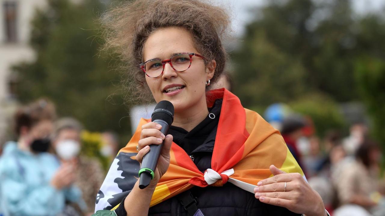 Porträt von Anna Emmendörfer, die in ein Mikrofon spricht. Porträt von Anna Emmendörfer, die in ein Mikrofon spricht.