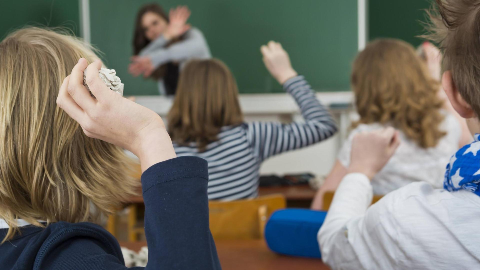 Schüler im Klassenzimmer bewerfen die Lehrerin mit Papierbällen, Mobbing gegen Lehrer