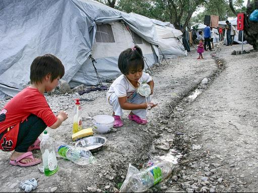 Zwei Flüchtlingskinder im Zeltlager beim Abwasch mit Wasserflaschen