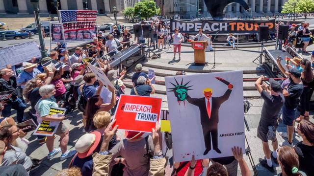 Demonstranten stehen mit Protestschildern rund um eine Rednerbühne am Foley Square in New York City.