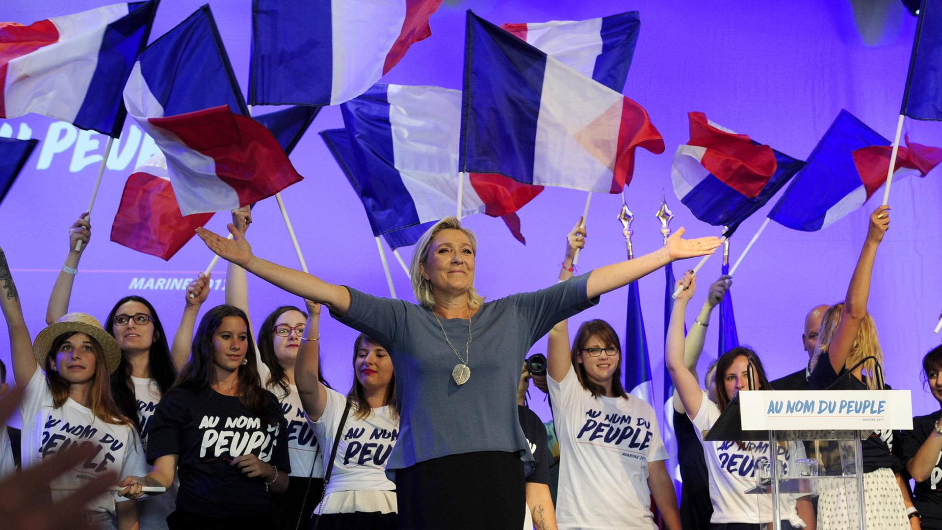 Marine Le Pen, Vorsitzende des rechtsextremen Front National, steht bei einem Kongress der Partei im südfranzösischen Frejus mit ausgebreiteten Armen auf der Bühne. Marine Le Pen, Vorsitzende des rechtsextremen Front National, steht bei einem Kongress der Partei im südfranzösischen Frejus mit ausgebreiteten Armen auf der Bühne.