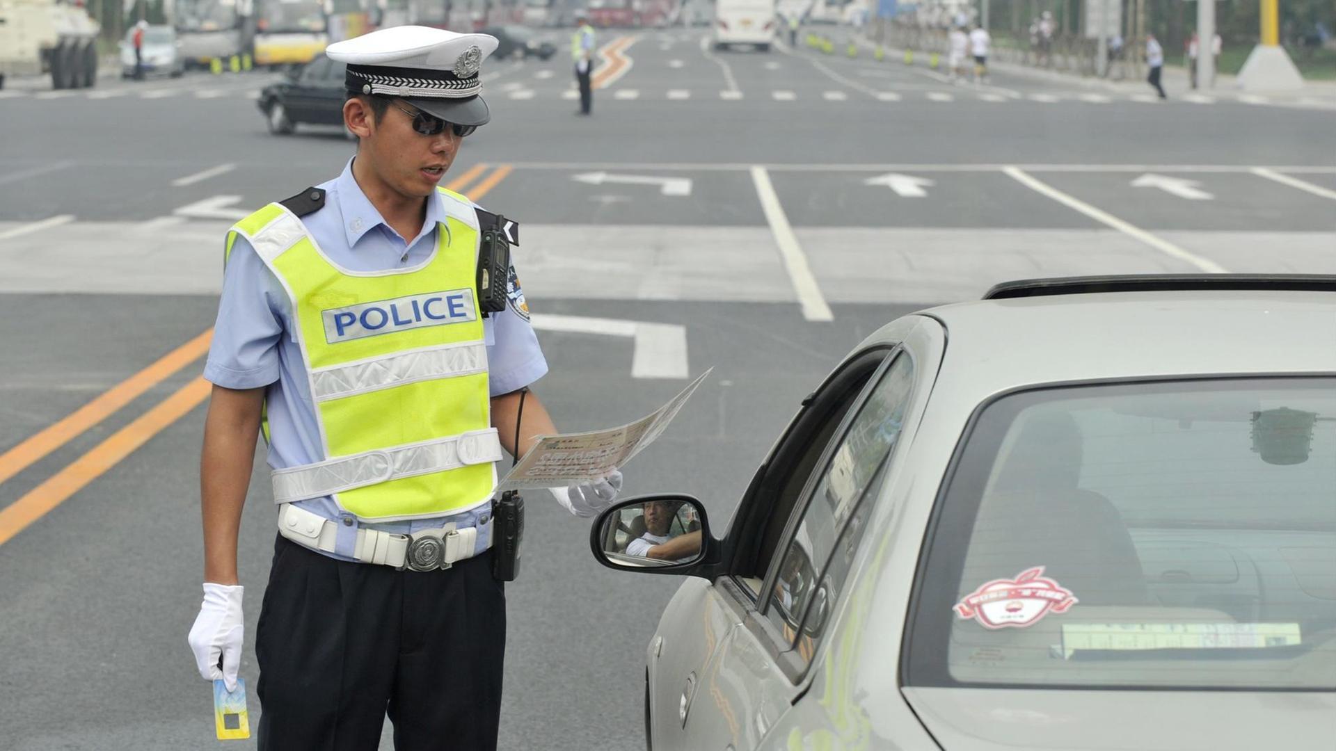 Ein chinesischer Polizist kontrolliert einen Autofahrer. Ein chinesischer Polizist kontrolliert einen Autofahrer.