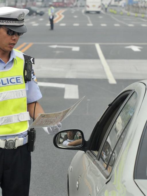Ein chinesischer Polizist kontrolliert einen Autofahrer.