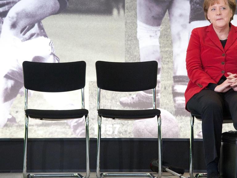 Bundeskanzlerin Merkel legt ihr Bein auf einen Koffer