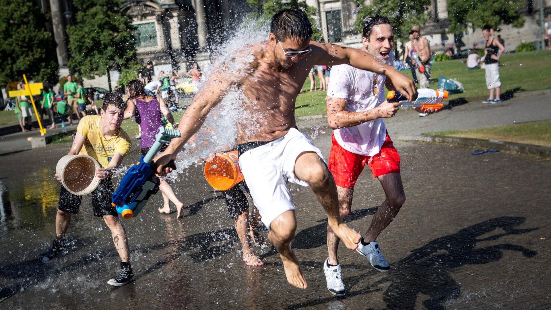 Wasserschlacht im Sommer mit mehreren Menschen, die Wasser aus Eimern aufeinander kippen. Wasserschlacht im Sommer mit mehreren Menschen, die Wasser aus Eimern aufeinander kippen.