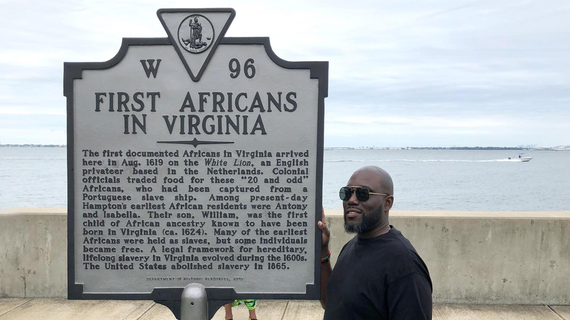 Ein Mann steht neben einer Gedenktafel in Fort Monroe, die an die Ankunft im Jahr 1619 des ersten Schiffes erinnert, das Sklaven nach Virginia brachte.