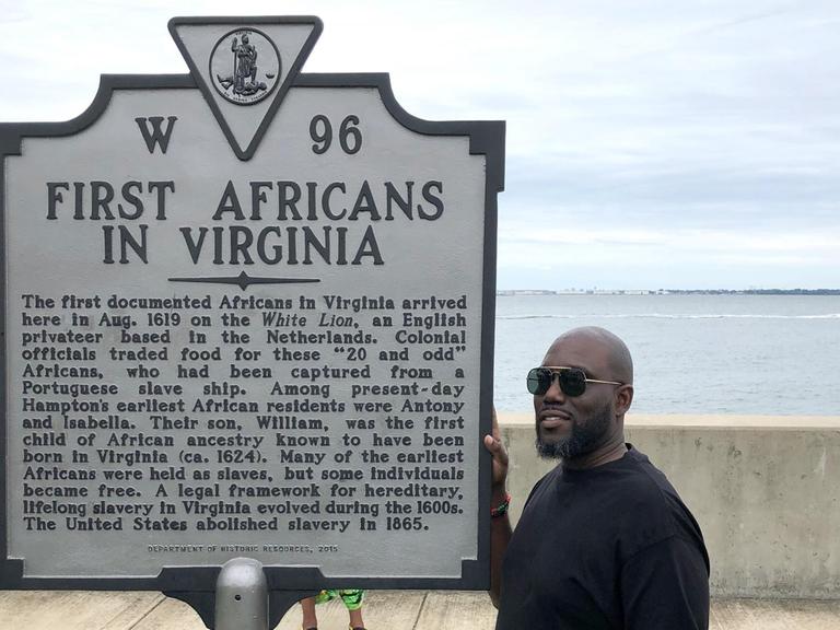 Ein Mann steht neben einer Gedenktafel in Fort Monroe, die an die Ankunft im Jahr 1619 des ersten Schiffes erinnert, das Sklaven nach Virginia brachte.