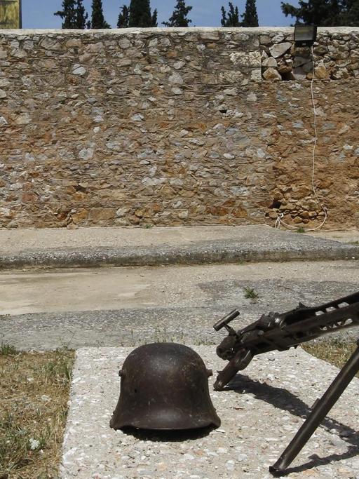 Ein Helm und ein Maschinengewehr aus der Zeit der deutschen Besatzung liegen an der Gedenkstätte im Park Skopeftirioin in Athen.