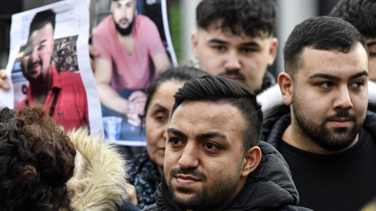 Freunde und Verwandte der Opfer des rechten Terroranschlags von Hanau stehen in einer Gruppe und halten Bilder hoch Freunde und Verwandte der Opfer des rechten Terroranschlags von Hanau stehen in einer Gruppe und halten Bilder hoch