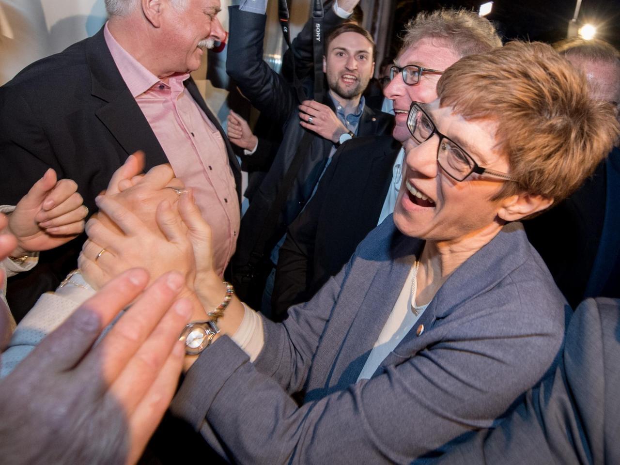 Kramp-Karrenbauer schüttelt lachend die Hände von Parteifreunden.