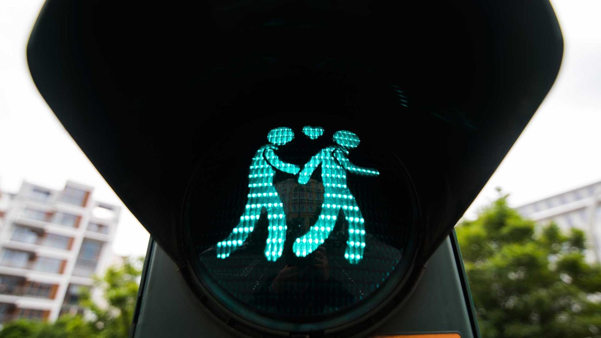 Eine Ampel zeigt ein homosexuelles Paar, das Händchen hält.
Eine Ampel zeigt ein homosexuelles Paar, das Händchen hält.