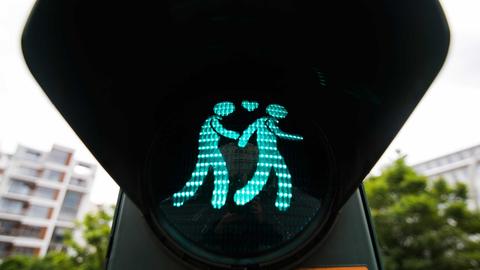 Eine Ampel zeigt ein homosexuelles Paar, das Händchen hält.
