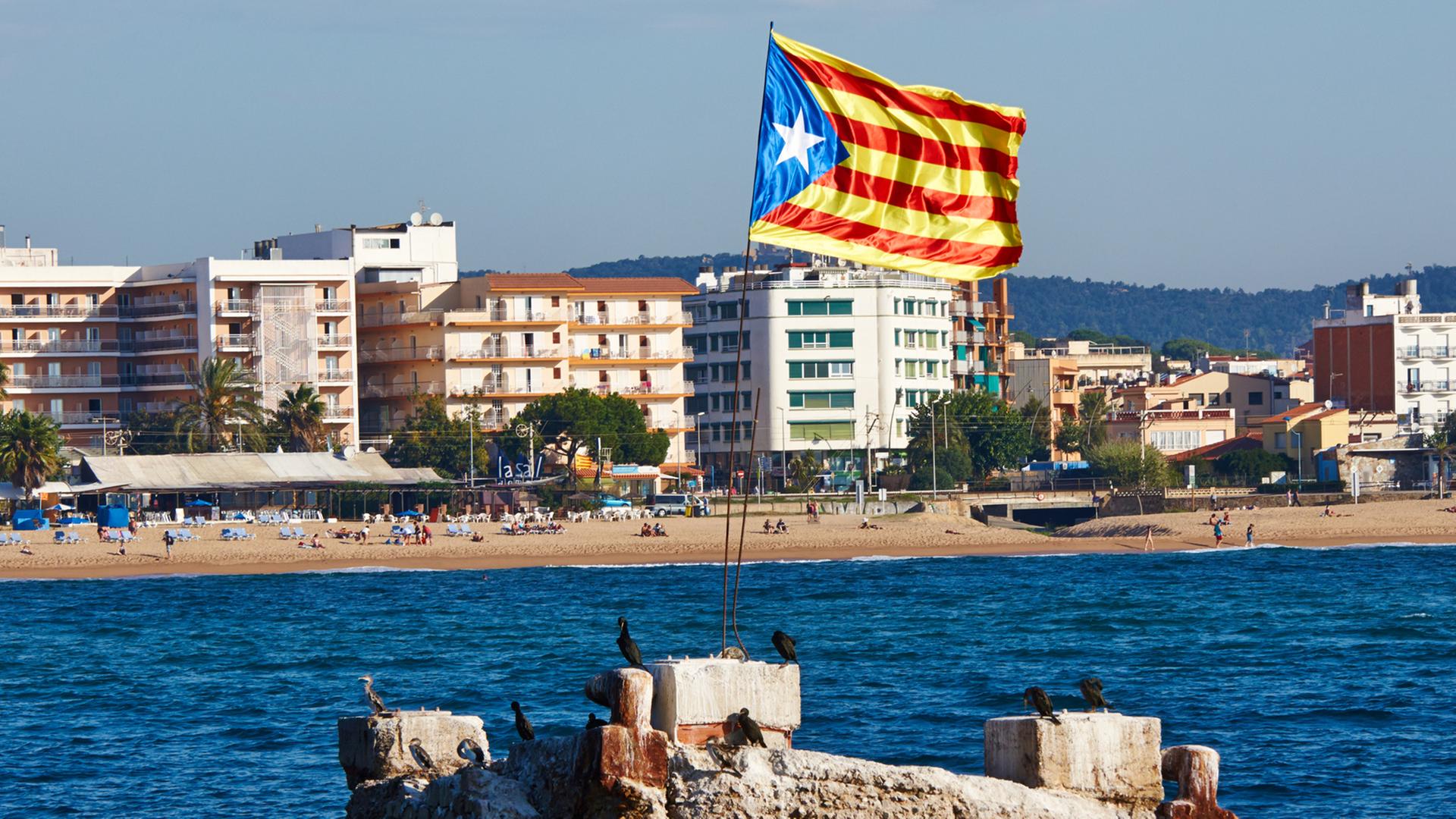 Ein Felsen im Meer vor der Küste Kataloniens, auf der eine katalanische Flagge im Wind weht. Ein Felsen im Meer vor der Küste Kataloniens, auf der eine katalanische Flagge im Wind weht.