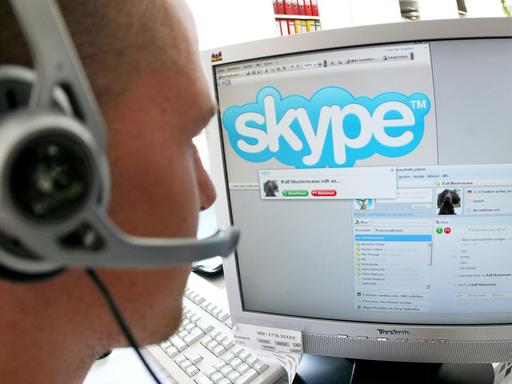 Ein junger Mann sitzt in Frankfurt am Main mit einem Headset vor einem Computerbildschirm und nutzt Skype, ein Programm, das unter anderem Internet-Telefonie ermöglicht.
