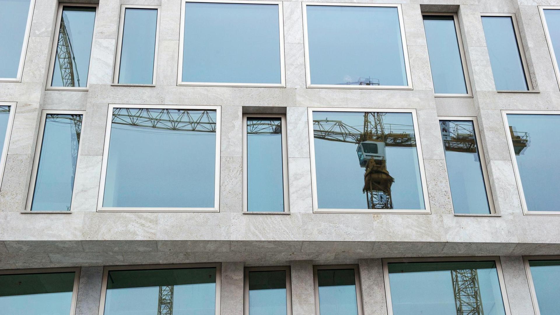 Ein Baukran spiegelt sich in Berlin in den Fenstern eines Gebäudes.