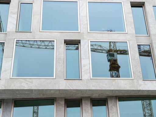 Ein Baukran spiegelt sich in Berlin in den Fenstern eines Gebäudes.