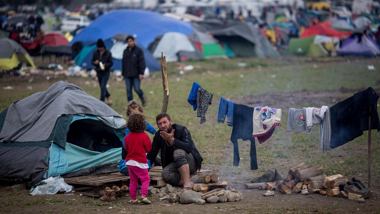 Ein Mann mit zwei Kindern sitzt am 11.03.2016 vor seinem Zelt im Flüchtlingslager in Idomeni an der Grenze zwischen Griechenland und Mazedonien. Ein Mann mit zwei Kindern sitzt am 11.03.2016 vor seinem Zelt im Flüchtlingslager in Idomeni an der Grenze zwischen Griechenland und Mazedonien.