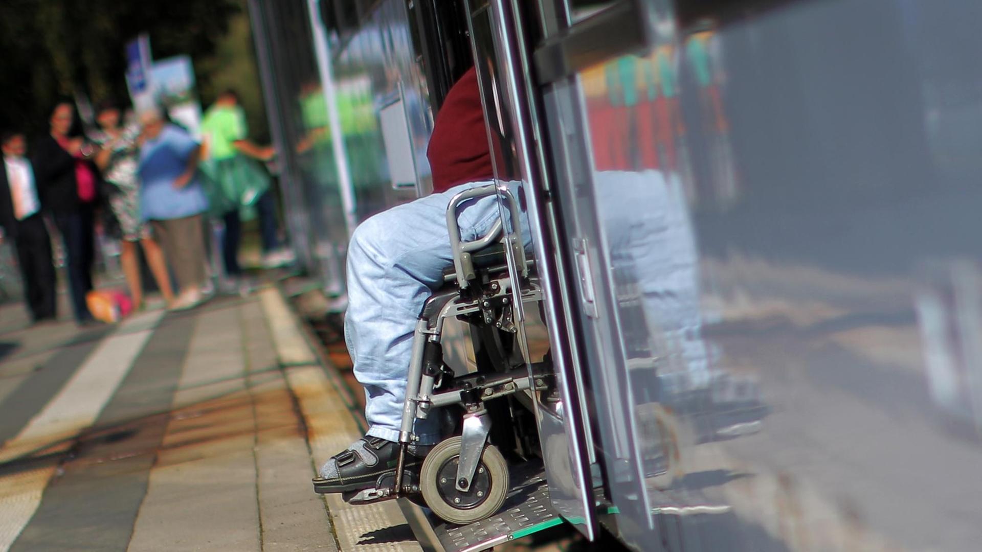 Ein Mann fährt in einem Rollstuhl aus einem Zug. Ein Mann fährt in einem Rollstuhl aus einem Zug.