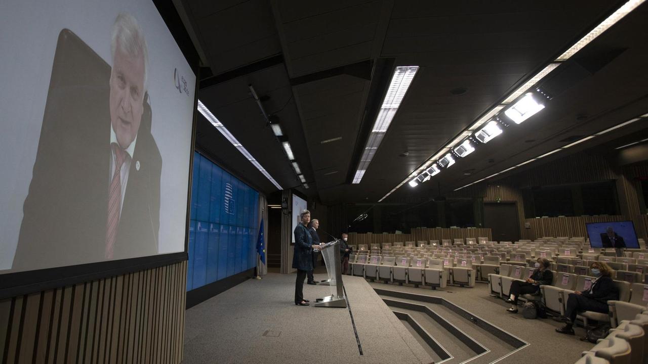 Ein Live-Stream von Horst Seehofers Rede wird in einem fast leeren Auditorium an die Wand projiziert. Ein Live-Stream von Horst Seehofers Rede wird in einem fast leeren Auditorium an die Wand projiziert.