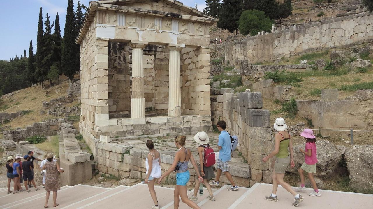 Besucher spazieren durch die ehemalige Schatzkammer der Athener an der alten archäologischen Stätte von Delphi in Griechenland. Besucher spazieren durch die ehemalige Schatzkammer der Athener an der alten archäologischen Stätte von Delphi in Griechenland.