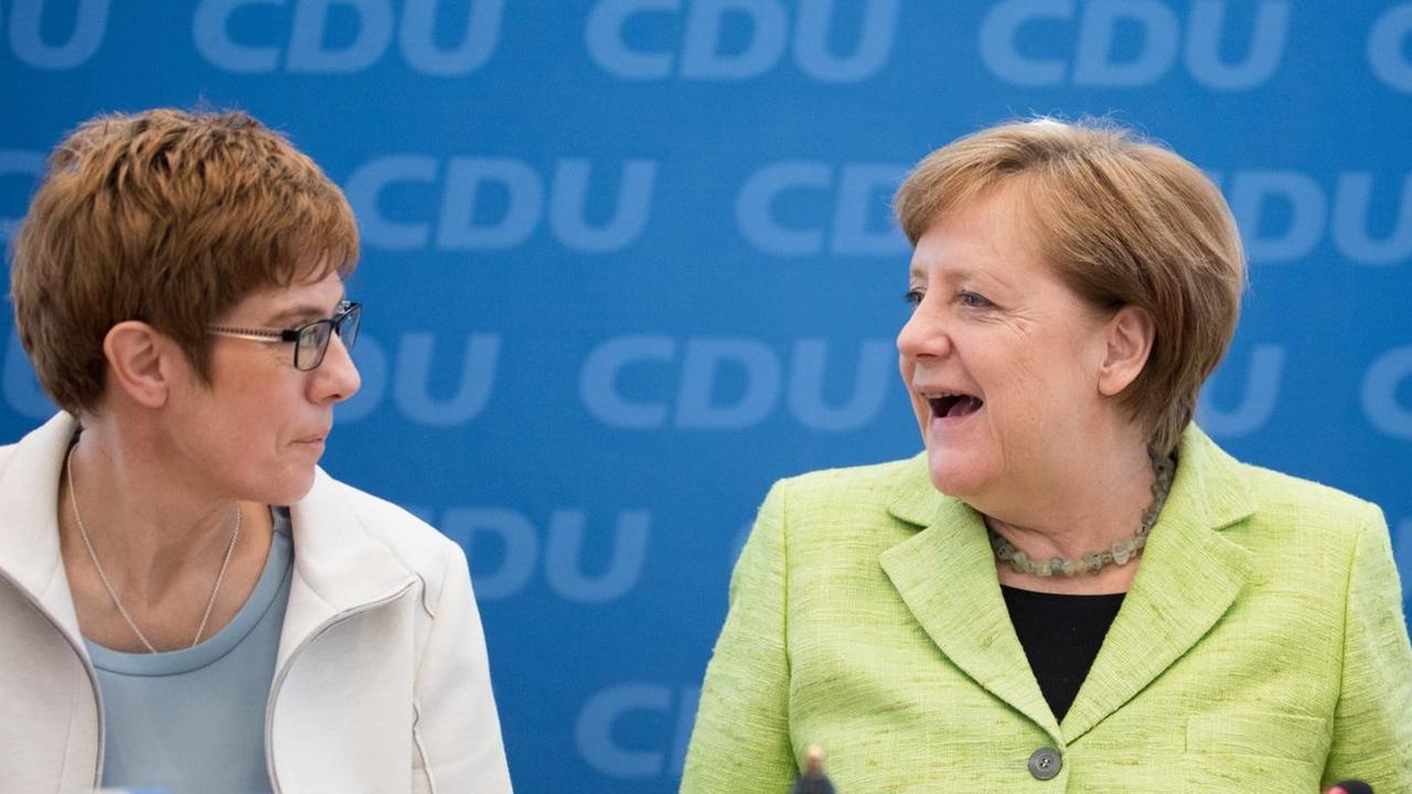 Die saarländische Ministerpräsidentin Kramp-Karrenbauer und CDU-Chefin Merkel blicken sich an. Die saarländische Ministerpräsidentin Kramp-Karrenbauer und CDU-Chefin Merkel blicken sich an.