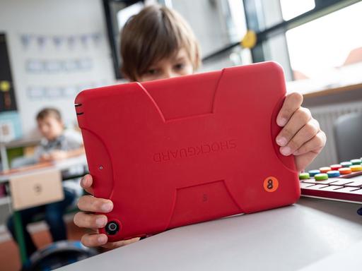 Ein junger Mensch arbeitet in einem Klassenzimmer in Baden-Württemberg mit einem Tablet.
