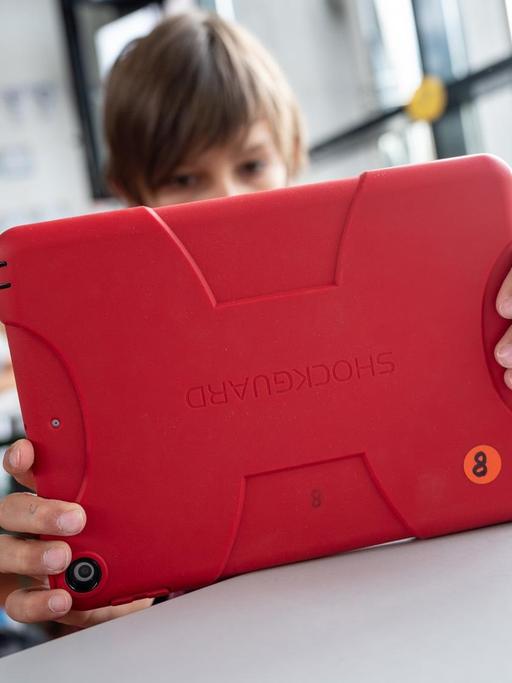 Ein junger Mensch arbeitet in einem Klassenzimmer in Baden-Württemberg mit einem Tablet.