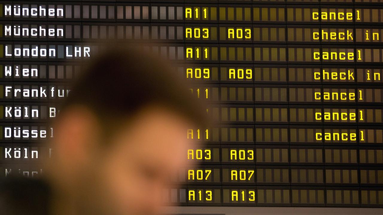 Ein Fluggast wartet auf dem Flughafen Berlin Tegel vor einer Anzeigetafel, auf der die Lufthansa-Flüge mit dem Vermerk "cancel" versehen sind.