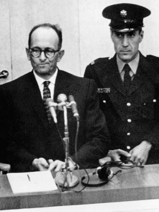 Adolf Eichmann steht am 4. November 1961 umringt von Wärtern vor Gericht in Jerusalem.