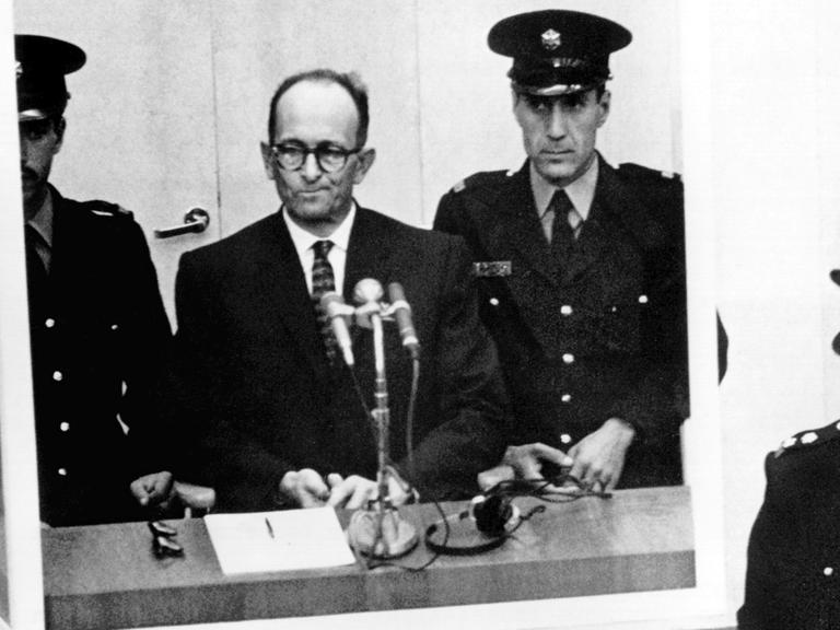 Adolf Eichmann steht am 4. November 1961 umringt von Wärtern vor Gericht in Jerusalem.