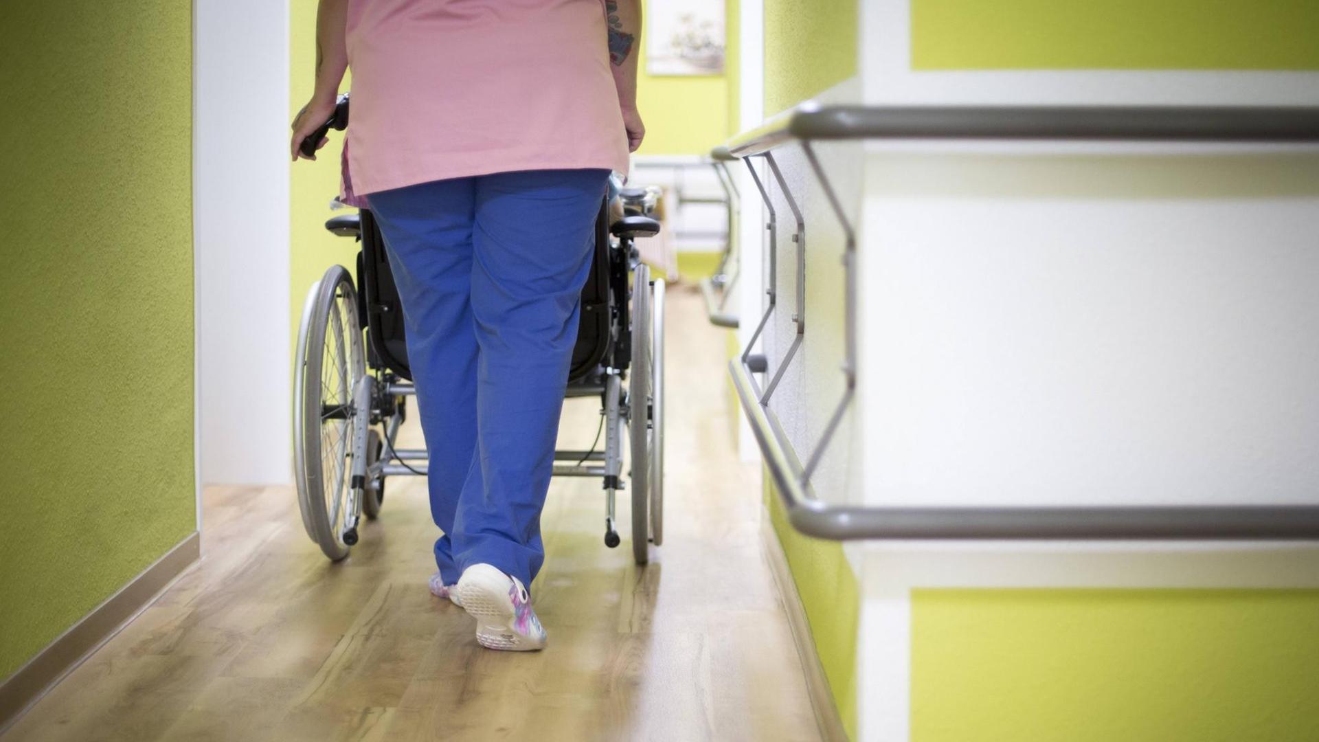 Eine Altenpflegerin schiebt eine Bewohnerin in einem Altenpflegeheim in einem Rollstuhl den Gang entlang. Eine Altenpflegerin schiebt eine Bewohnerin in einem Altenpflegeheim in einem Rollstuhl den Gang entlang.